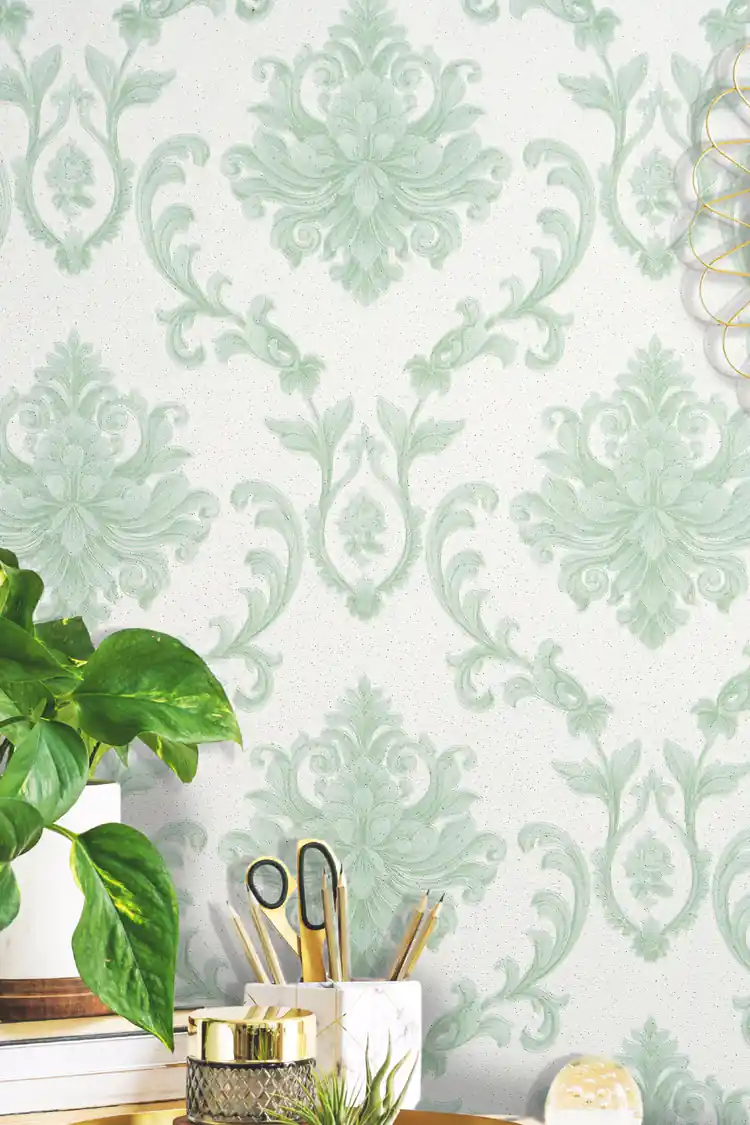 Close-up of the green damask motif on the installed wall with desk accessories and indoor plant