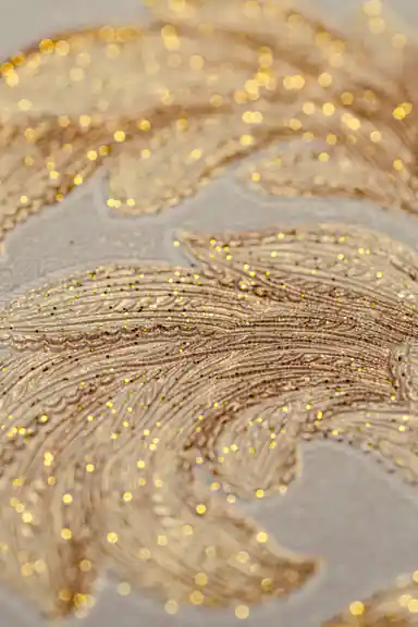 Extreme macro close-up of the sparkling gold glitter embedded in the embossed leaf pattern
