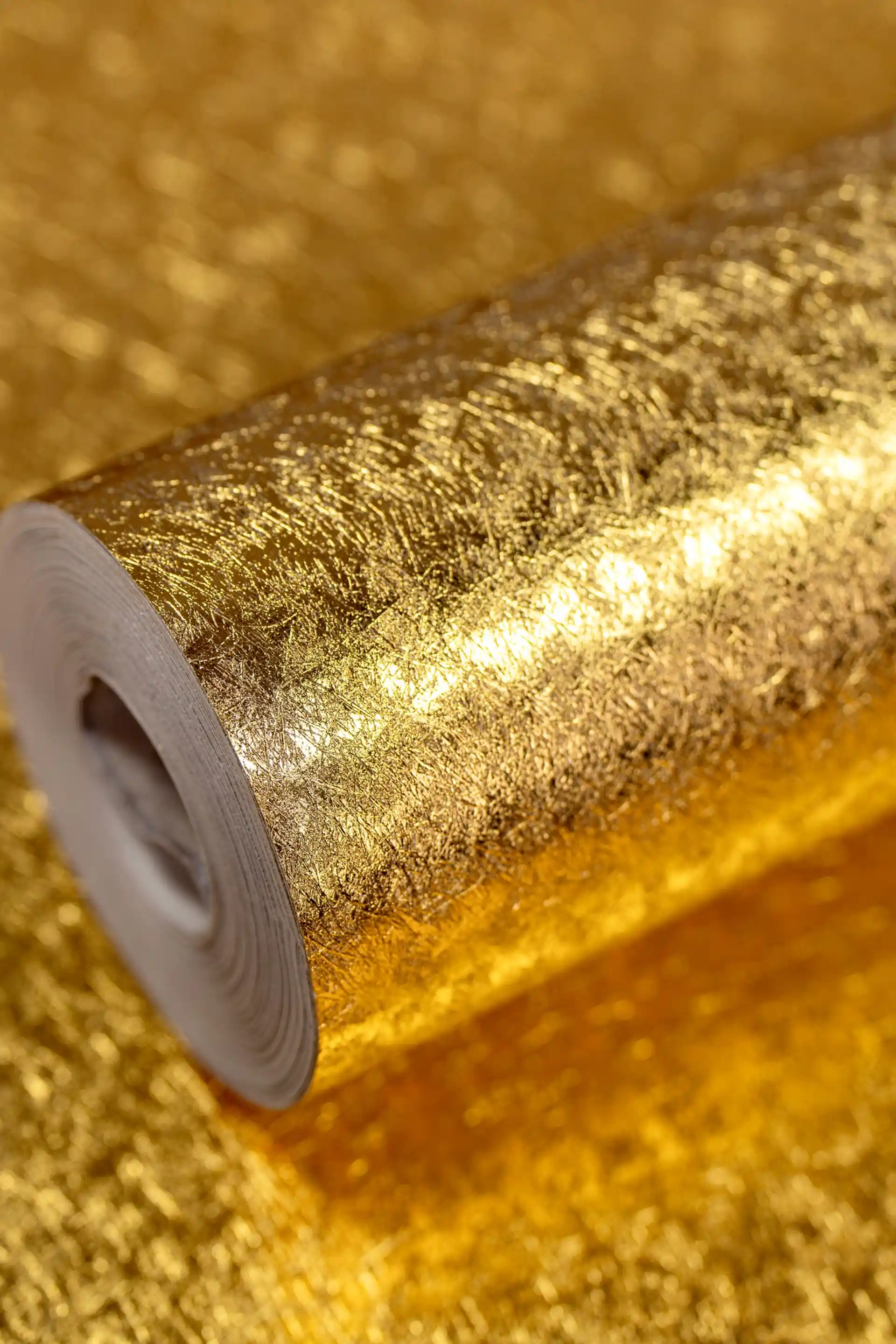 Shiny metallic golden foil wallpaper roll with a brilliant reflective crinkled texture surface