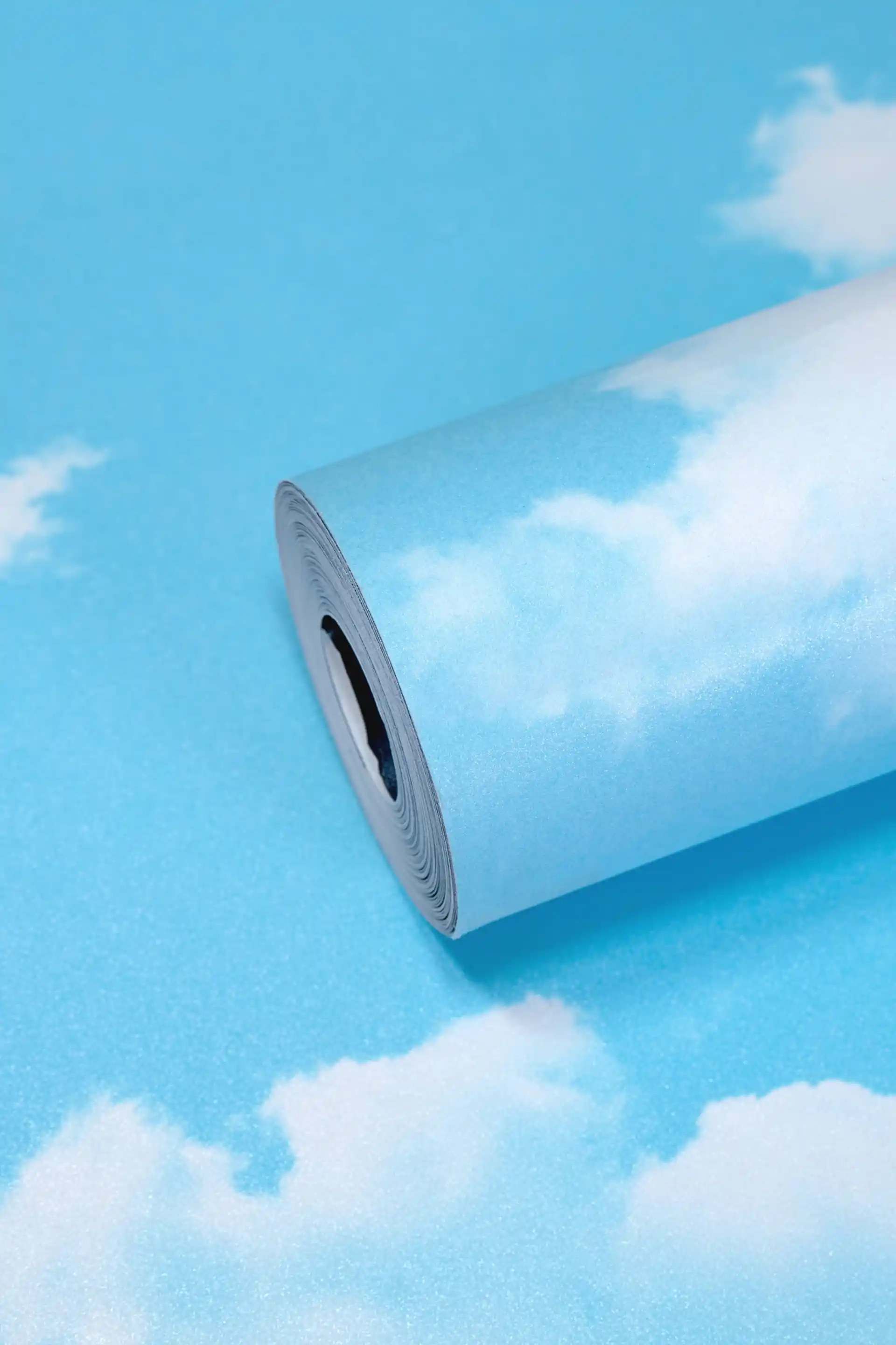 Bright blue sky wallpaper roll with scattered white fluffy cloud pattern on a vivid cyan background