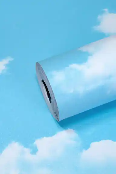 Bright blue sky wallpaper roll with scattered white fluffy cloud pattern on a vivid cyan background