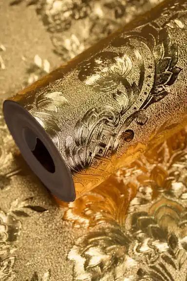Elegant entryway with gold foil damask wallpaper behind a dark wood dresser and sunburst mirror