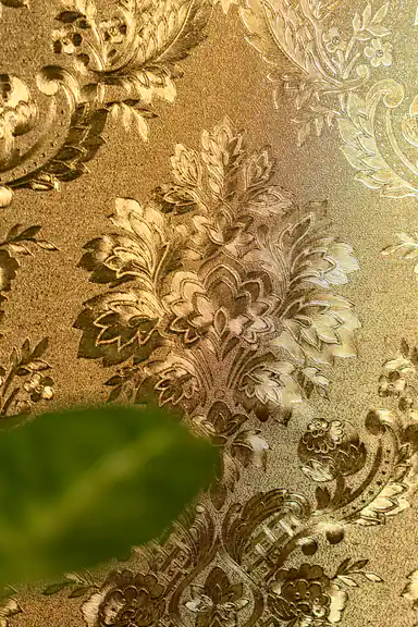 Close-up of the embossed gold foil floral motif with green leaf blurred in the foreground