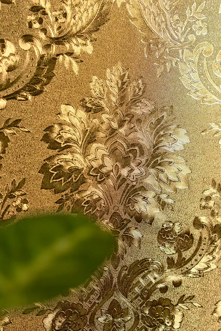 Close-up of the embossed gold foil floral motif with green leaf blurred in the foreground