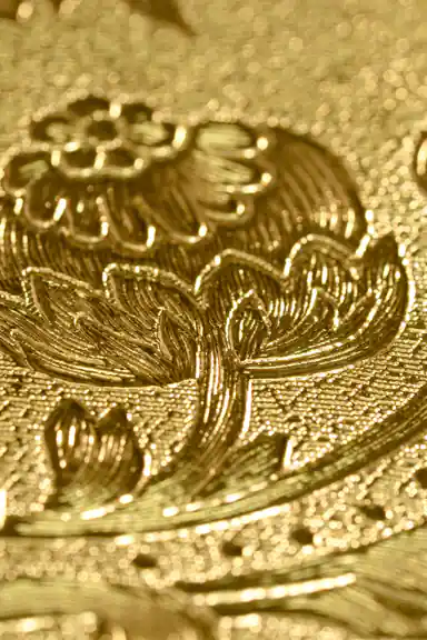 Extreme macro detail of the embossed gold baroque pattern showing intricate flower and leaf engraving