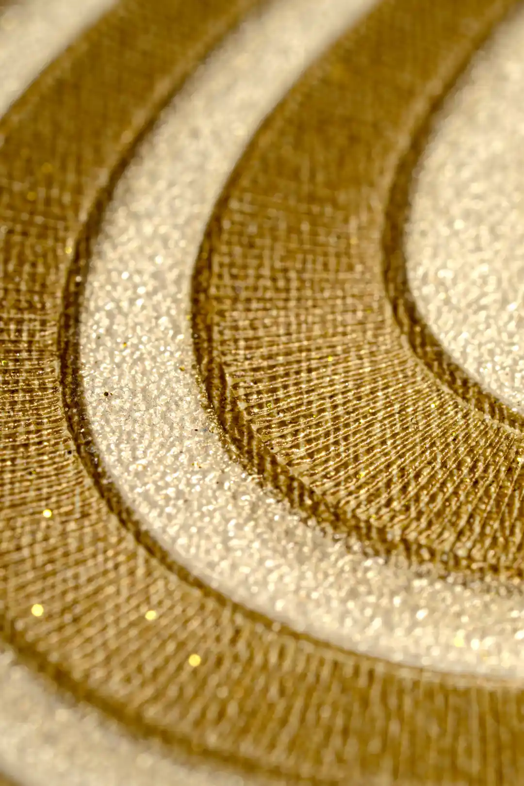 Extreme macro of the glitter-accented gold and cream wavy line texture showing surface depth