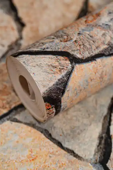 Close-up of the wallpaper roll showing realistic cracked stone texture in orange, grey, and brown tones