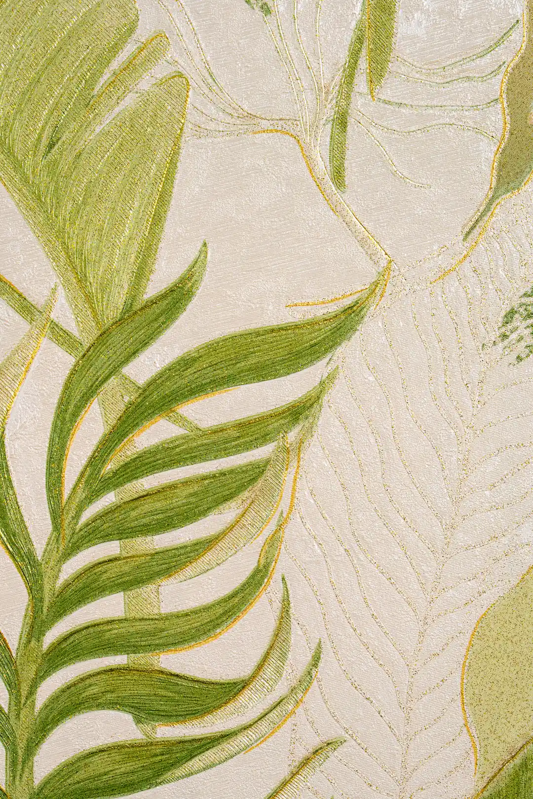 Flat lay detail of green palm fronds with gold-edged veins on an ivory textured wallpaper surface