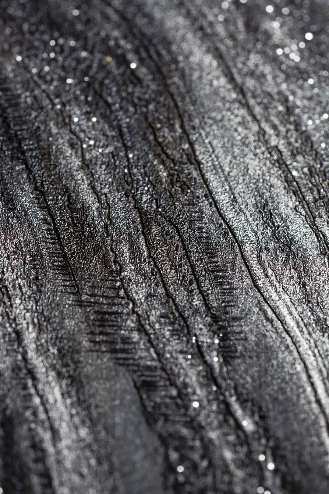 Extreme macro detail of silver glitter particles embedded in the black and grey marble swirl texture
