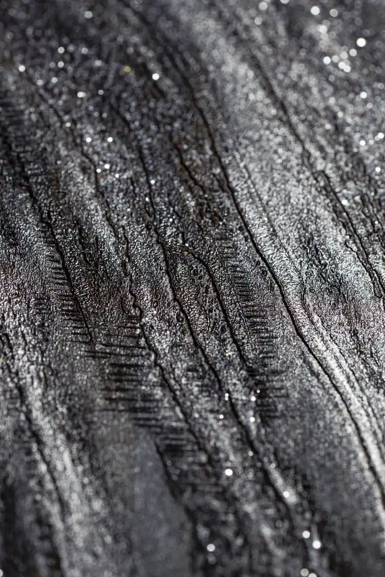 Extreme macro detail of silver glitter particles embedded in the black and grey marble swirl texture