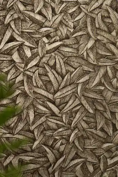 Close-up flat view of tightly packed metallic bronze leaves with a hint of green foliage at edge