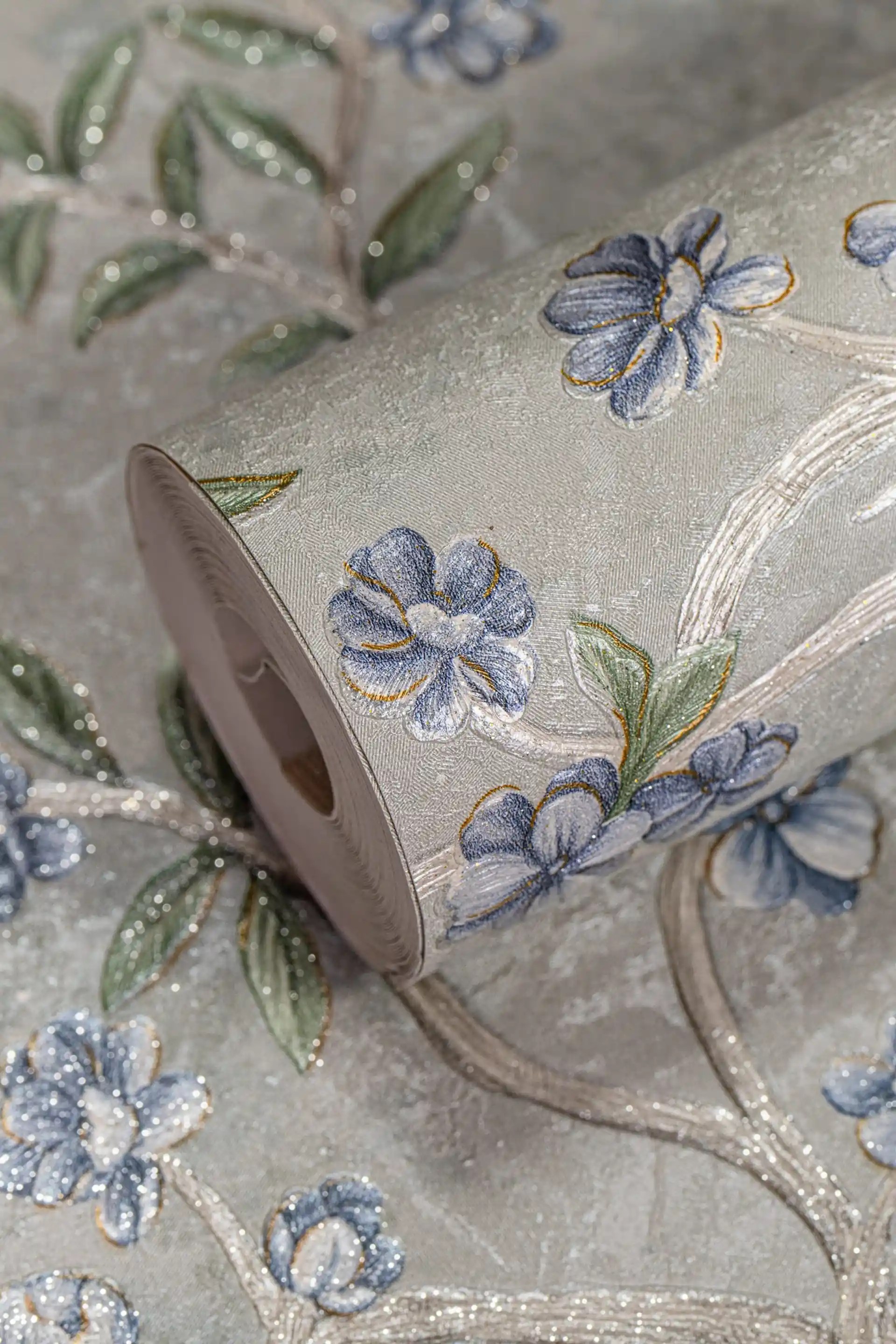 Wallpaper roll with blue blossom tree motif and glitter accents on a light grey-green background