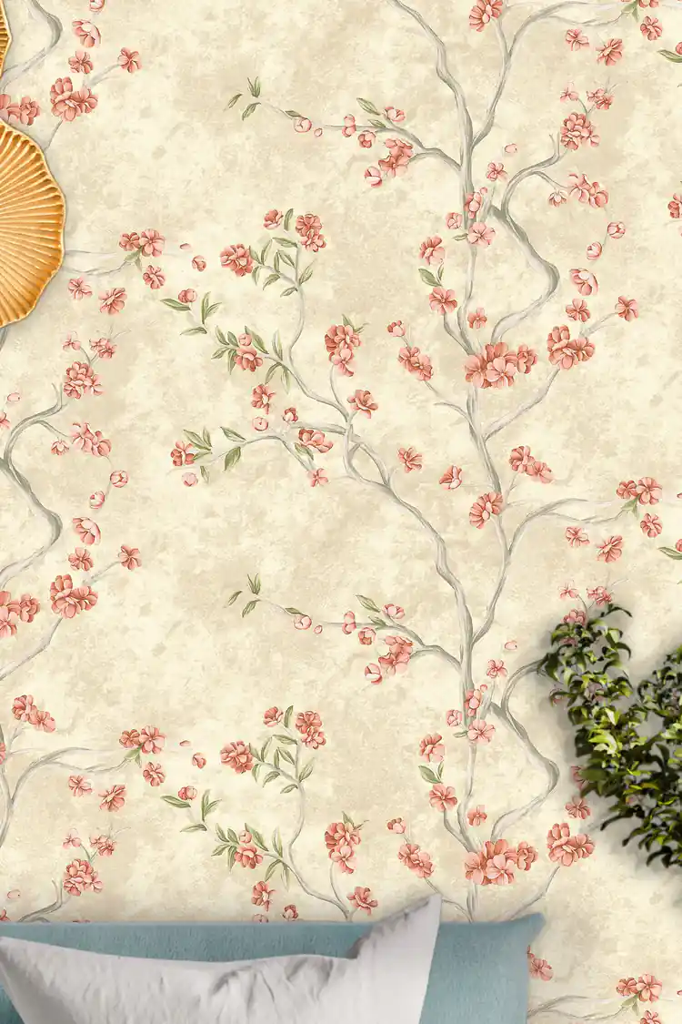 Close-up of pink cherry blossom branches scattered across an ivory wallpaper with a golden decorative piece on the wall