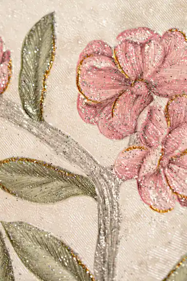 Macro detail of pink blossoms with gold glitter edges, silver branches, and green leaves on ivory wallpaper