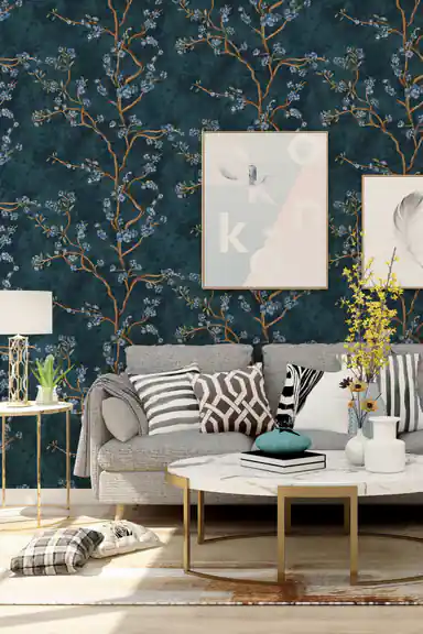 Elegant living room with deep teal floral wallpaper featuring blue blossoms behind a grey sofa and art prints