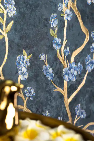 Medium close-up of blue flower clusters on gold branches against a dark teal textured wallpaper background