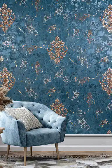 Living room scene with teal baroque wallpaper behind a blue tufted armchair and feathered vase