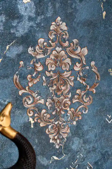 Close-up of a single ornate bronze baroque medallion on the rich teal textured wallpaper surface