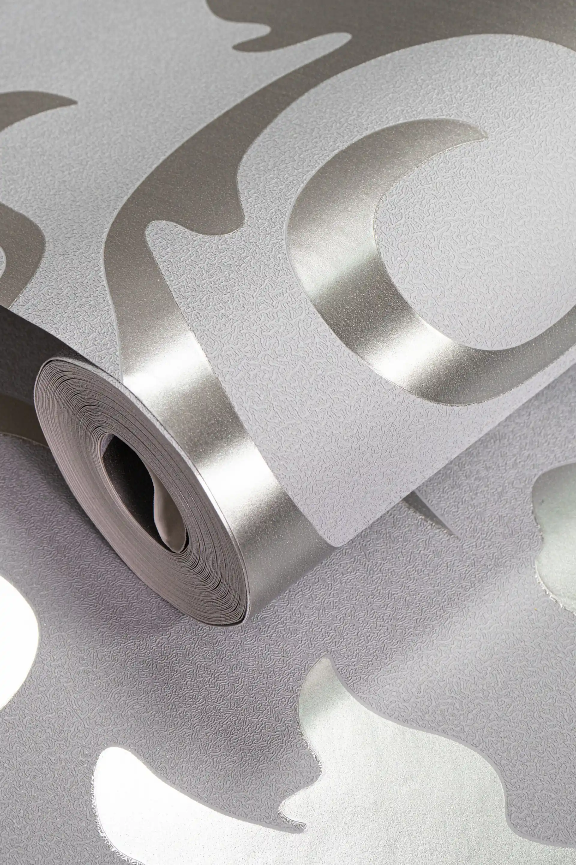 Rolled grey wallpaper with silver metallic scrollwork curves and a shimmer finish