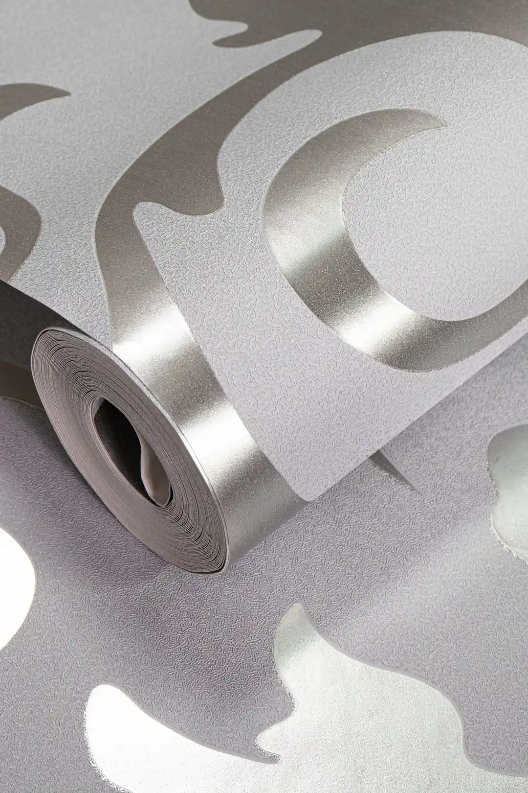 Rolled grey wallpaper with silver metallic scrollwork curves and a shimmer finish