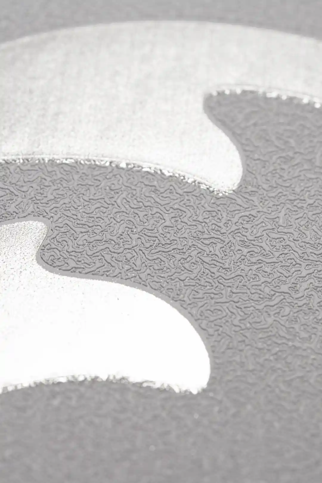 Extreme macro showing the silver glitter shimmer texture along a single curve on grey wallpaper