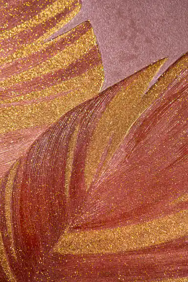 Close-up macro of gold glitter veins running through a burgundy palm leaf on rose-toned wallpaper