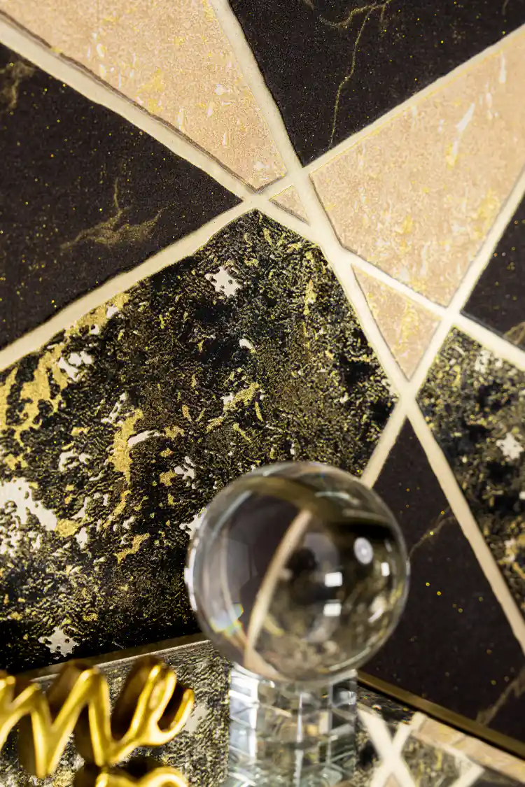 Close-up of black and golden geometric triangle wallpaper with marble texture and glitter finish