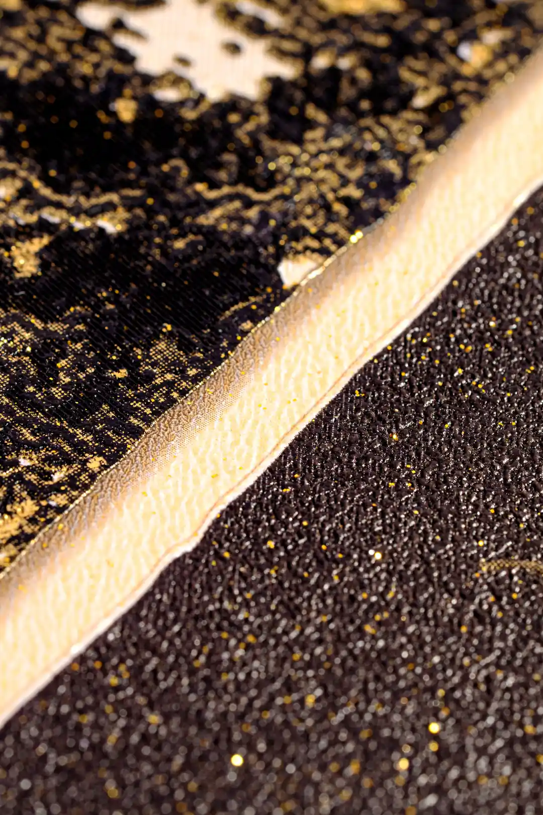 Extreme macro of gold glitter edge detail between dark marble sections on the geometric wallpaper