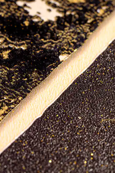 Extreme macro of gold glitter edge detail between dark marble sections on the geometric wallpaper