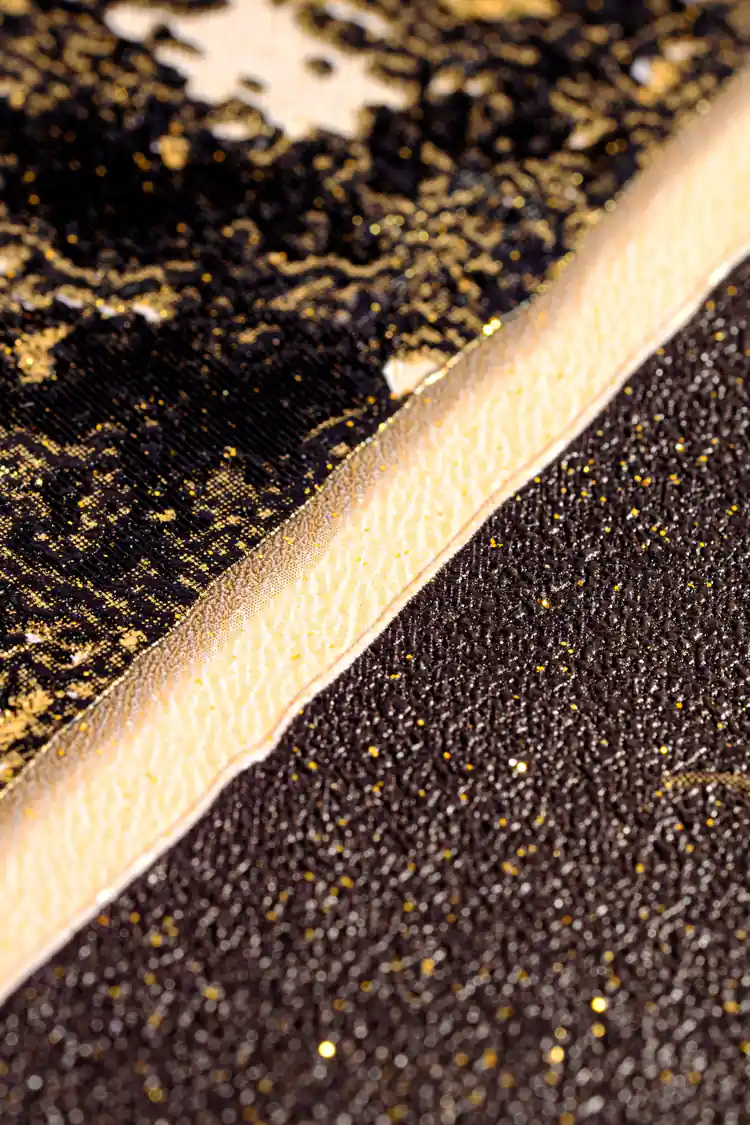 Extreme macro of gold glitter edge detail between dark marble sections on the geometric wallpaper