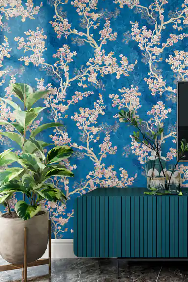Living room with blue cherry blossom wallpaper installed behind a teal ribbed sideboard and potted plants
