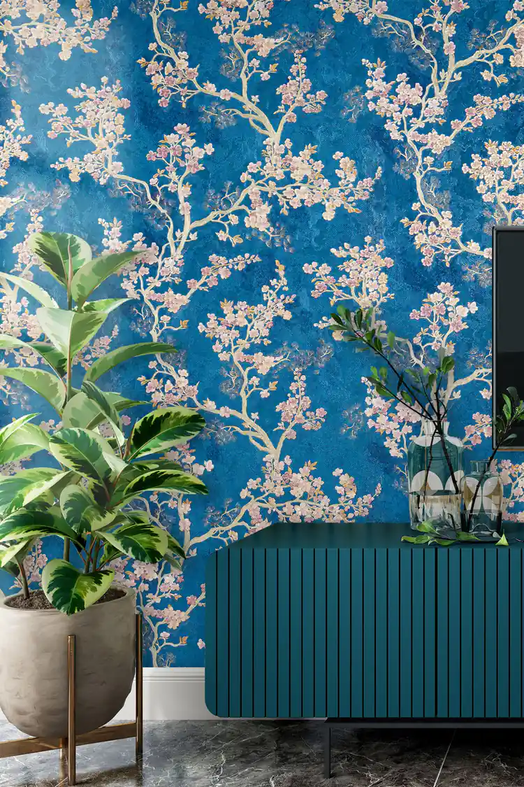 Living room with blue cherry blossom wallpaper installed behind a teal ribbed sideboard and potted plants