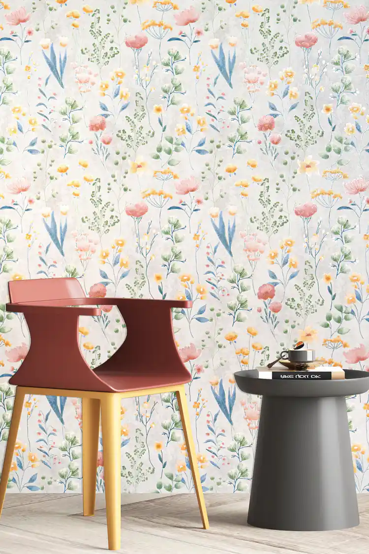Room scene with meadow flower wallpaper behind a coral-red chair and grey side table on light wood floor