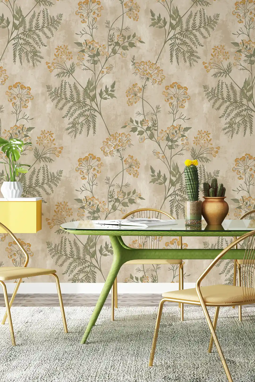 Dining area with beige botanical meadow wallpaper behind a green table, gold chairs, and potted cactus