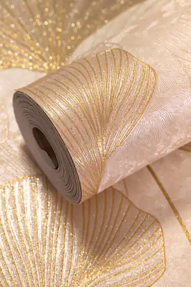 Rolled beige wallpaper with golden ginkgo leaf pattern and heavy glitter finish on a flat-lay surface
