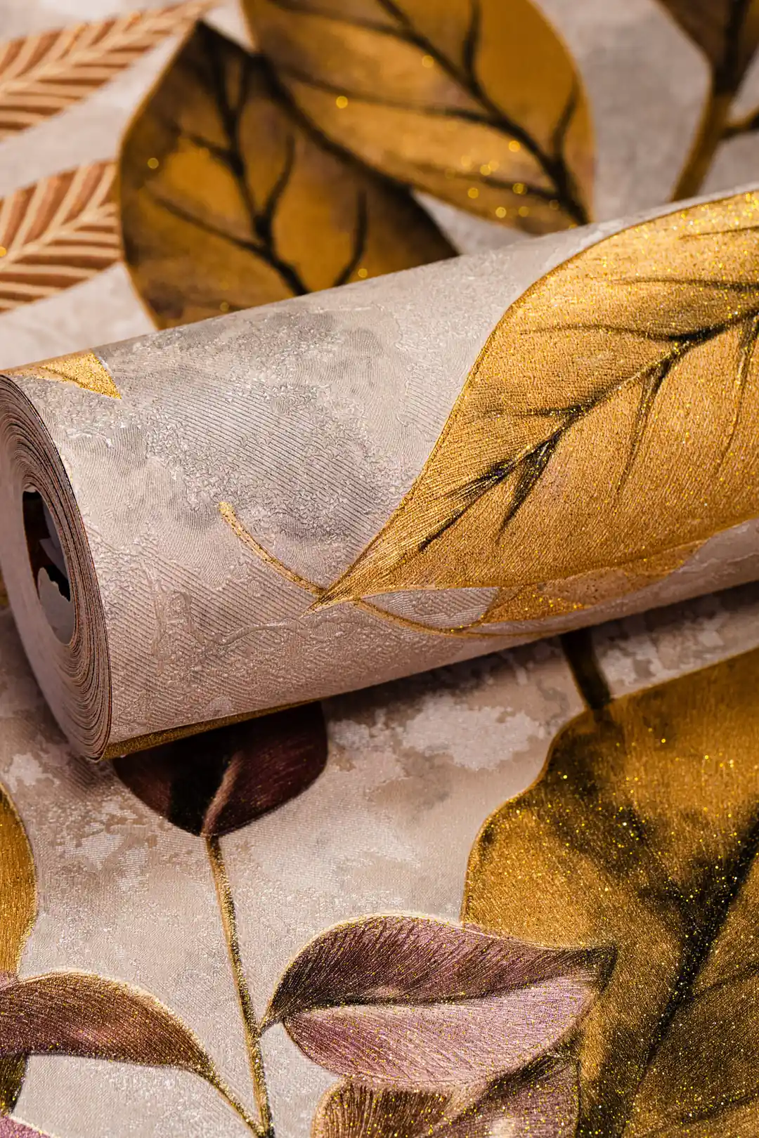 Rolled wallpaper displaying warm golden autumn leaves with shimmer on a grey marbled background