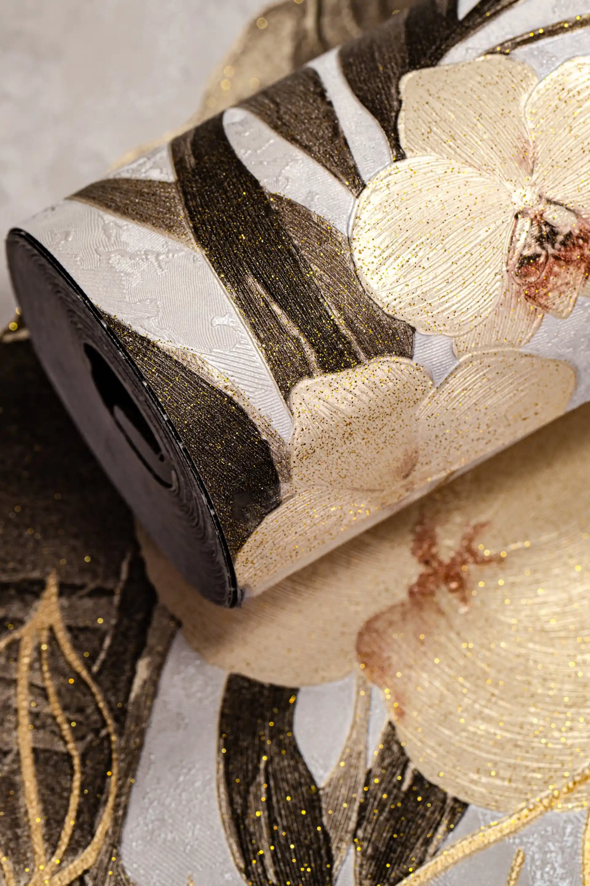 Rolled wallpaper featuring exotic orchids and dark ferns with copper glitter accents on a cream background