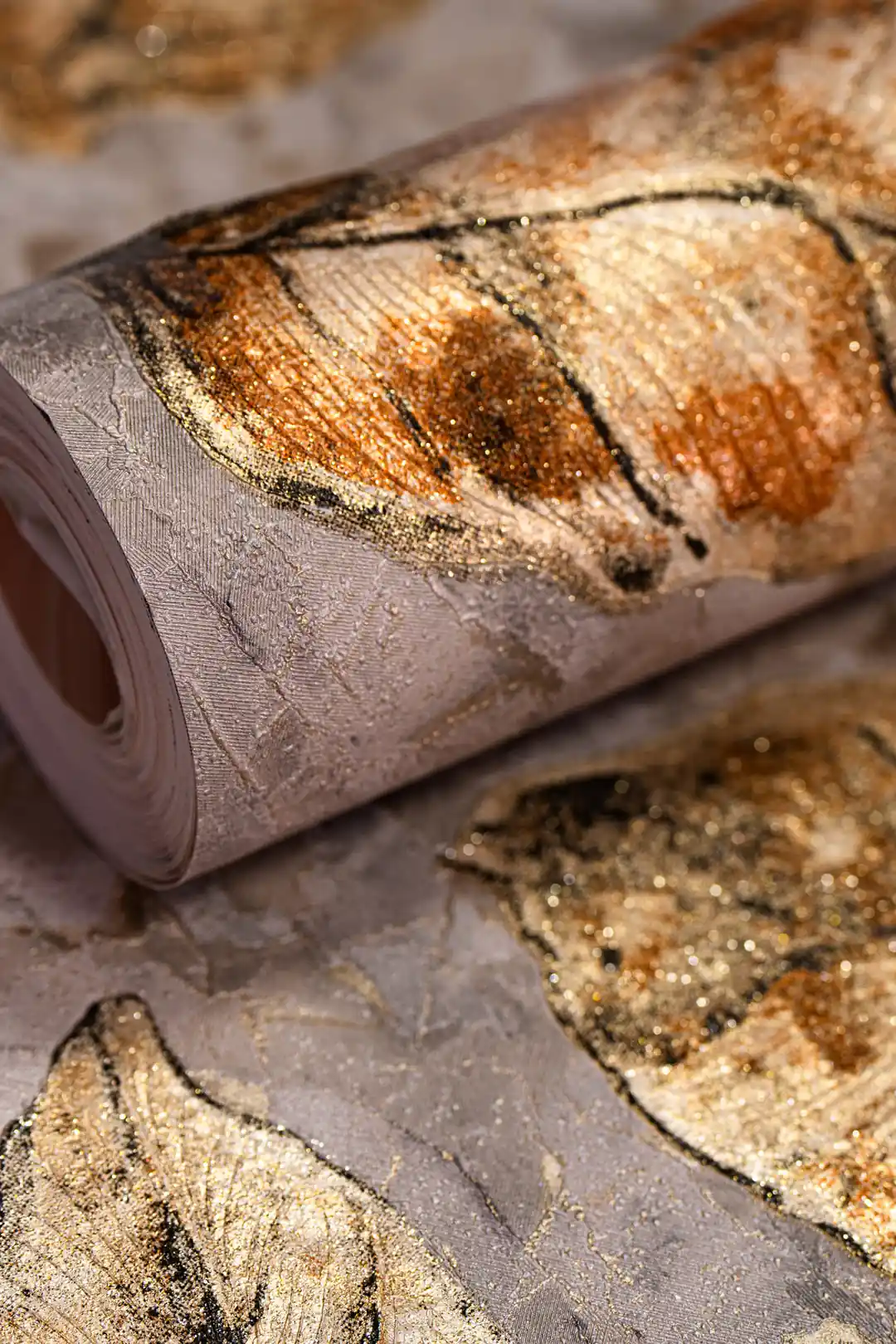 Rolled wallpaper showcasing autumn brown fallen leaves with golden glitter on a mauve textured background