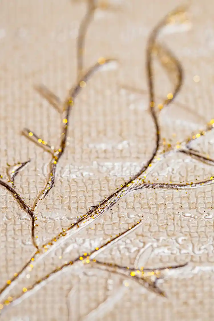 Extreme macro of gold glitter twig detail showing sparkling particles on woven beige wallpaper texture