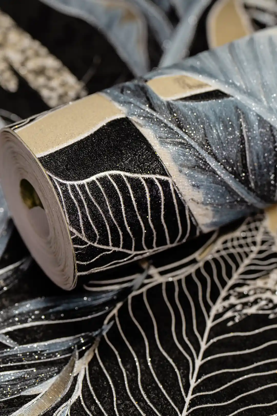 Rolled dark wallpaper featuring midnight jungle banana leaves in blue and black with glitter shimmer
