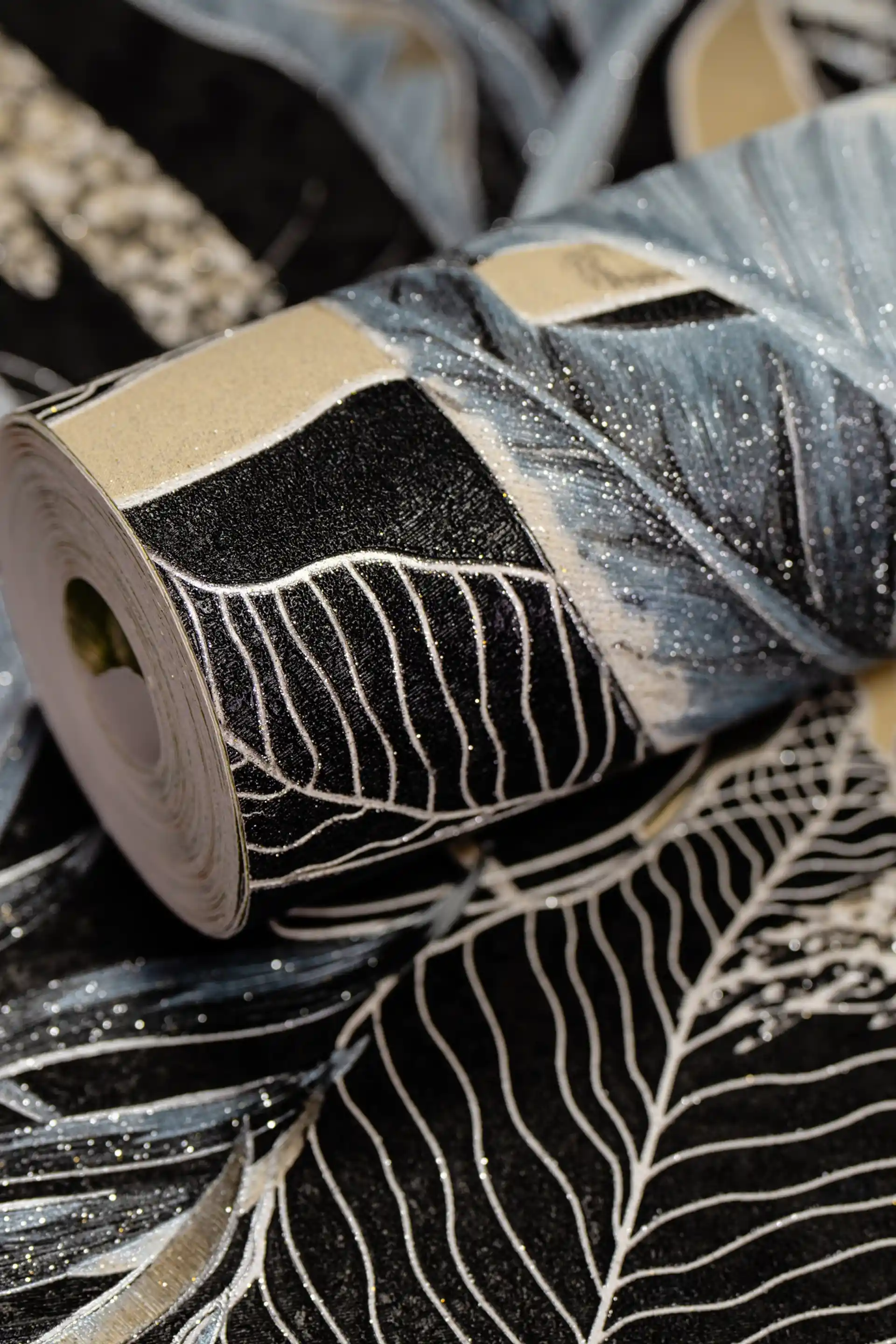 Rolled dark wallpaper featuring midnight jungle banana leaves in blue and black with glitter shimmer