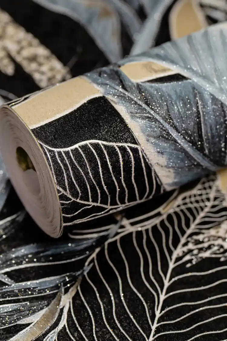 Rolled dark wallpaper featuring midnight jungle banana leaves in blue and black with glitter shimmer
