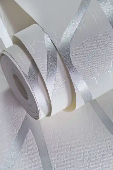 Rolled white wallpaper showing silver metallic swirl pattern with textured crackle base close-up