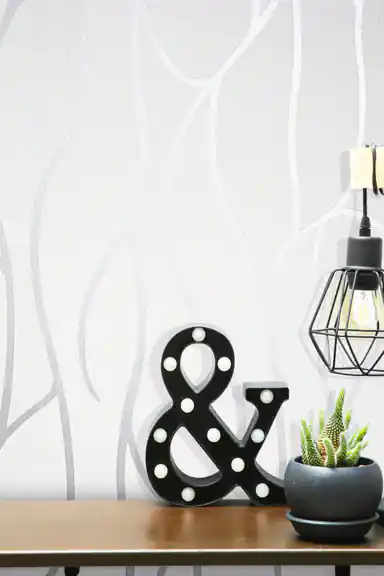 Silver swirl wallpaper close-up with decorative ampersand marquee light and industrial cage pendant