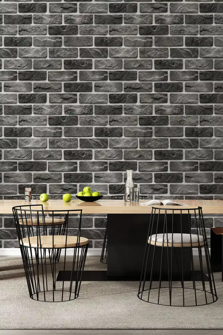 Charcoal grey stone brick wallpaper installed in a dining room with a modern table and wire-frame chairs