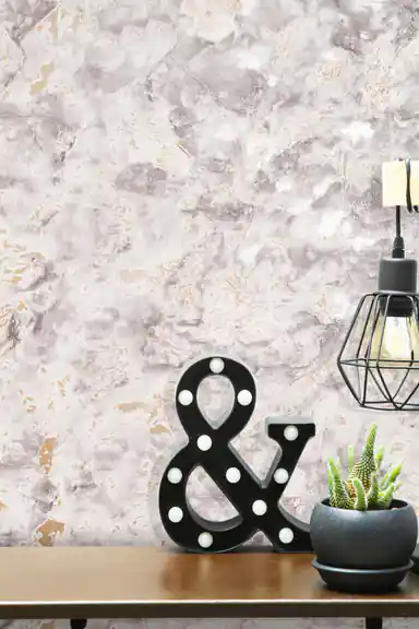 Close-up of grey marble wallpaper with gold accents and decorative ampersand marquee light on a shelf