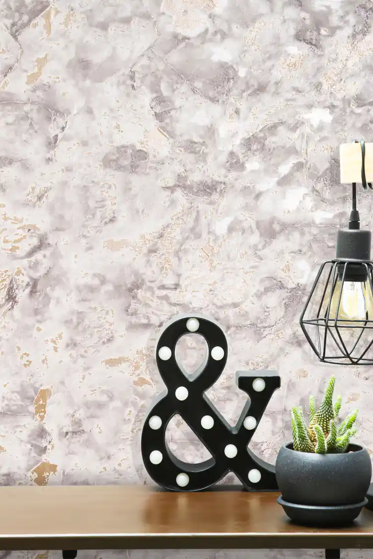 Close-up of grey marble wallpaper with gold accents and decorative ampersand marquee light on a shelf