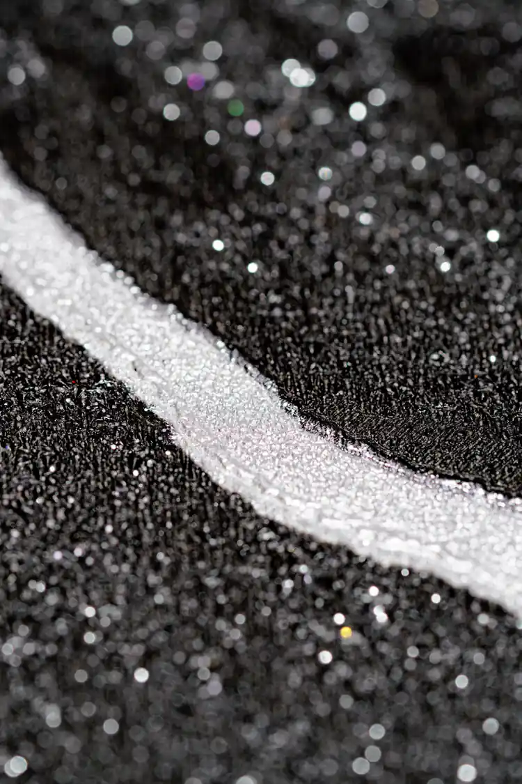 Extreme macro of silver line detail on black glitter wallpaper showing sparkling particle texture
