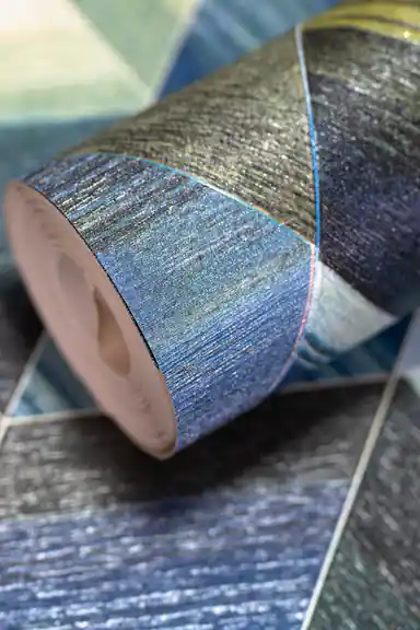 Rolled wallpaper with 3D geometric triangle tiles in blue, green, and gold tones on a textured surface
