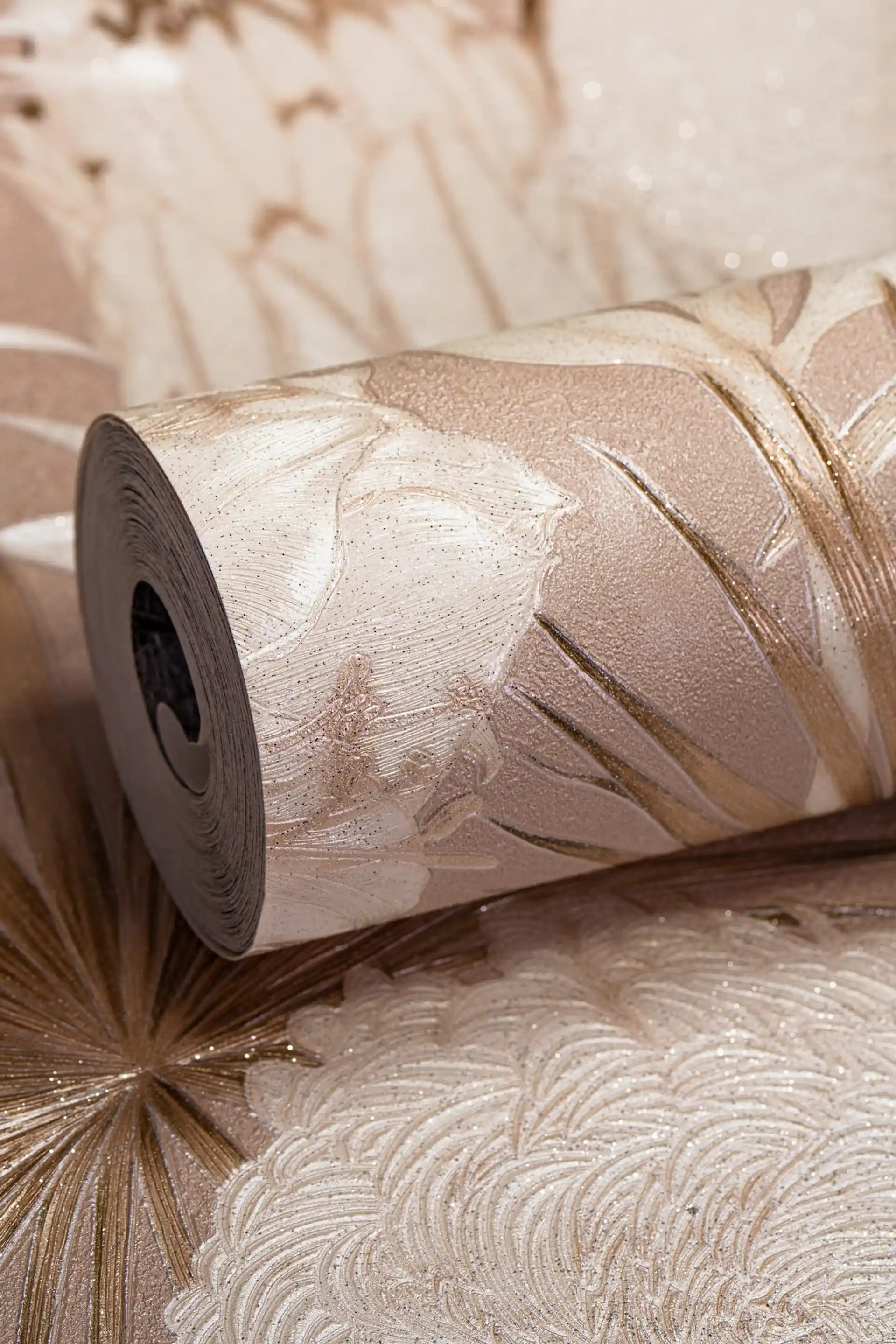 Rolled rose gold wallpaper with large shimmer flower and starburst pattern on a cream-pink textured base